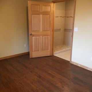 An empty room with wooden flooring and an open closet door showing shelves.