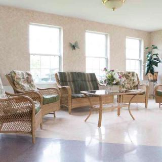 A bright living room featuring wicker furniture and a glass table.