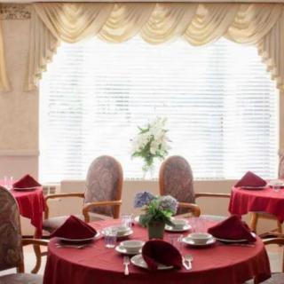 A formal dining area with red tablecloths, neatly arranged settings, and elegant curtains.