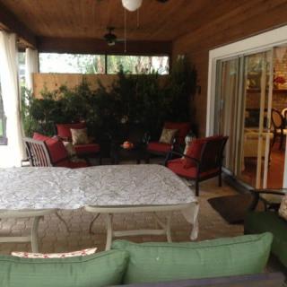 A cozy outdoor patio with red-cushioned seating and a large table under a covered roof.