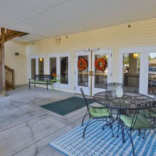 A cozy outdoor patio with a table and chairs, complete with decorative wreaths on the glass doors.