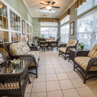 A bright sunroom with wicker furniture and large windows allowing natural light.