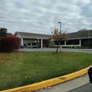 A view of a building surrounded by landscaped grass and trees under a cloudy sky.