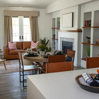 A modern living room featuring a dining table, sofa, and fireplace with surrounding shelves.