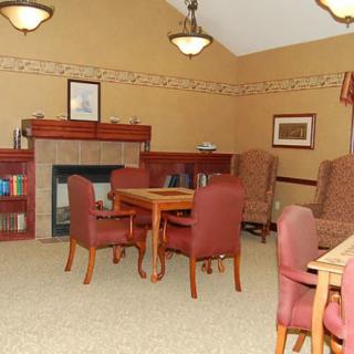 A cozy living room with a fireplace, armchairs, a table, and a bookshelf.