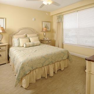 A cozy bedroom with a neatly made bed, bedside tables with lamps, and soft lighting.