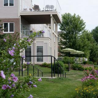 A scenic garden with blooming flowers and a view of a residential building with balconies and outdoor seating.