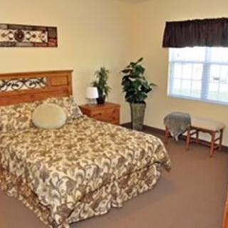A cozy bedroom with a bed, nightstand, and decorative plants.