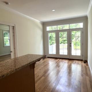 A bright and empty living room with hardwood floors and large glass doors leading outside.