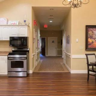 A cozy kitchen setup with a stove and microwave, leading into a hallway.