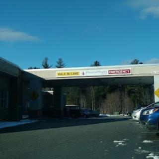 A view of a business entrance with clear blue skies and parked cars.