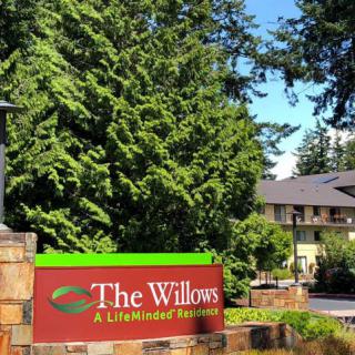 Entrance sign for The Willows retirement community surrounded by lush greenery.