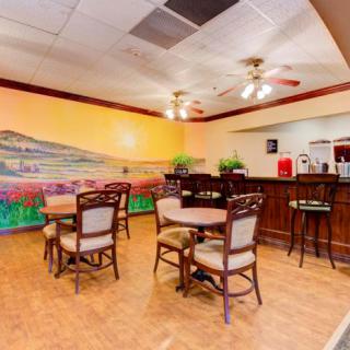 A cozy restaurant interior featuring a colorful mural, wooden tables and chairs, and a bar area.