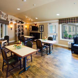 A cozy living room area with tables, chairs, and a fireplace.