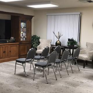 A small meeting room arranged with chairs facing a wooden cabinet and a decorative setup.