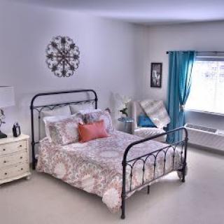 A cozy bedroom with decorative elements and a large window.
