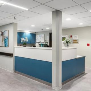 A modern reception area with a blue and white counter, well-lit interior, and minimalist decor.