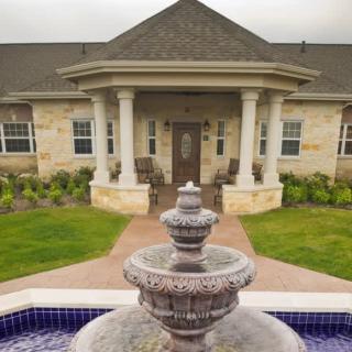 A charming house with a prominent fountain and landscaped entrance.