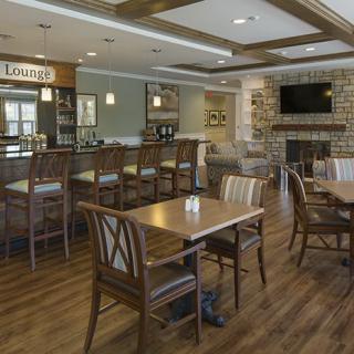 A cozy restaurant interior with a bar and dining tables, featuring wooden furniture and modern decor.