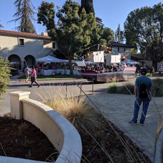 A lively outdoor event with people enjoying the atmosphere surrounded by trees and buildings.