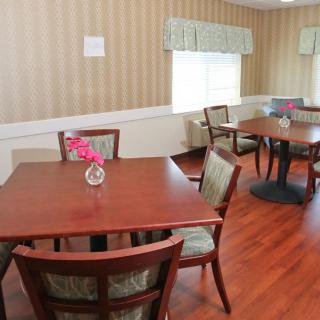 A cozy dining room with wooden tables and chairs, decorated with small vases of flowers.