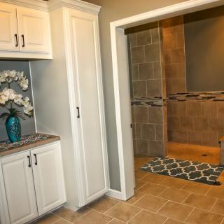 A modern bathroom featuring white cabinetry, a tiled shower area, and decorative elements.