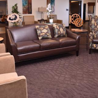A stylish lounge area featuring a brown leather sofa and patterned armchairs.