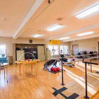 A well-lit rehabilitation center featuring various exercise equipment and training areas.