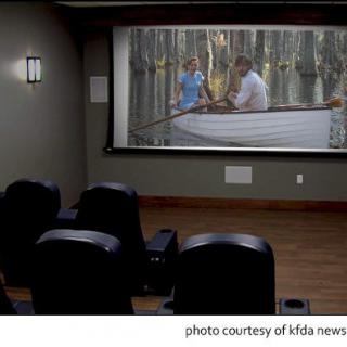 A cozy home theater setup with comfortable seating and a large screen displaying a movie.