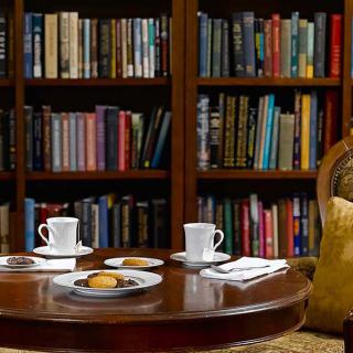 A cozy reading nook with a bookshelf, tea set, and cookies on a table.