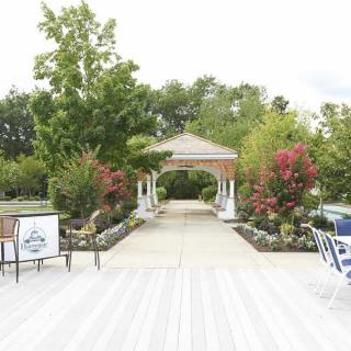 A serene garden pathway leading to a gazebo, surrounded by vibrant flowers and lush greenery.