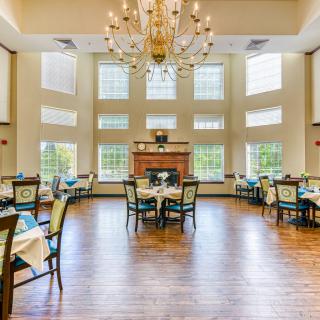 A spacious and elegant restaurant dining area with large windows and a central chandelier.