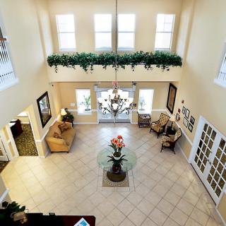 A spacious and elegantly decorated lobby with a chandelier, large windows, and comfortable seating.