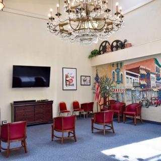 A cozy lobby area with red chairs, a chandelier, and wall decorations.