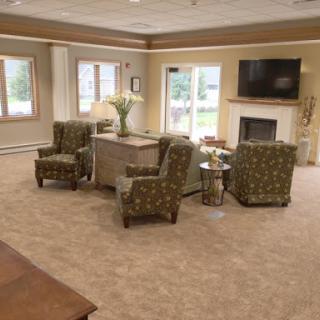 A cozy living room with comfortable chairs, a coffee table, and a television above the fireplace.