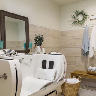 A modern bathroom featuring a luxury walk-in bathtub, a mirror, and tasteful decor with plants and towels.