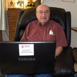 A person sitting in a chair using a Toshiba laptop indoors.
