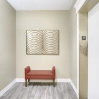 A minimalist hallway with a red bench and framed artwork on the wall.
