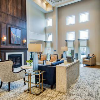 A modern living room with a high ceiling, featuring a fireplace and stylish furniture.