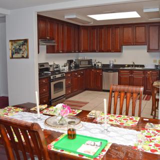A spacious kitchen and dining area featuring wooden cabinets and a well-set table.