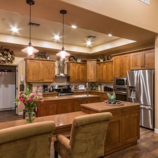 A modern kitchen featuring wooden cabinets, stainless steel appliances, and elegant lighting fixtures.