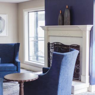 A modern living room with blue chairs, a fireplace, and elegant decor.