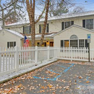 A quaint house with a white picket fence and snow-covered surroundings.