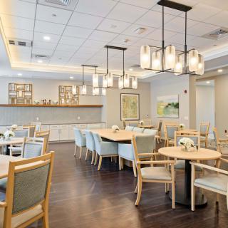 A modern dining room with neatly arranged tables and chairs, featuring contemporary lighting fixtures.