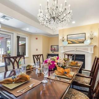 An elegant dining room with a chandelier and a beautifully set table, featuring floral centerpieces and warm decor.