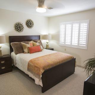 A cozy bedroom with a bed, decorative pillows, nightstands, and lamps.