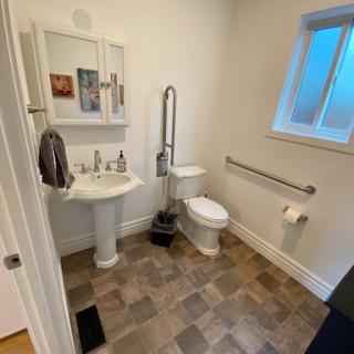 A clean and modern bathroom featuring a sink, toilet, and accessible grab bars.