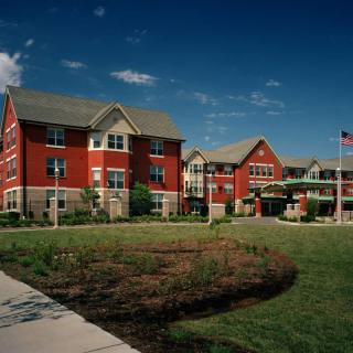 A large red-brick building with a well-maintained lawn and clear blue sky.