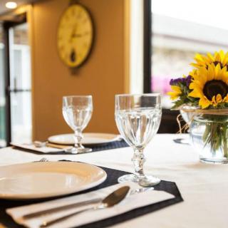 A beautifully set dining table featuring elegant glassware, white plates, and a sunflower centerpiece.