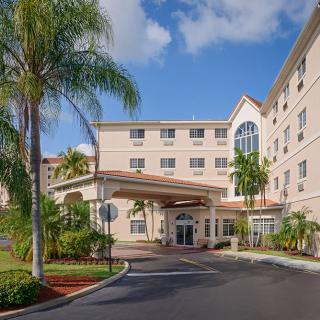 A tropical hotel entrance with palm trees under a blue sky.